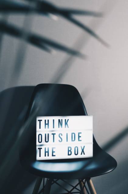 white sign with black words on black chair saying think outside the box
